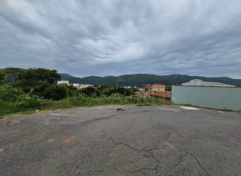 Terreno urbano com vista para montanhas em dia nublado. Asfalto rachado em primeiro plano.