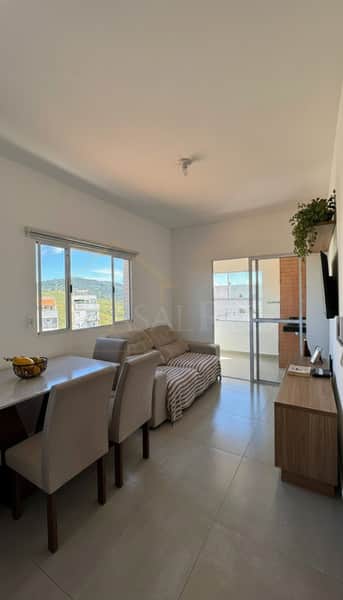 Sala iluminada com mesa, cadeiras, sofá e varanda. Decoração clean e moderna.