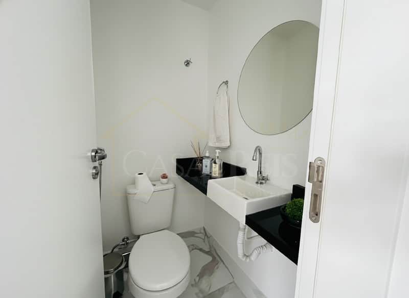 Banheiro clean com pia retangular, espelho redondo e vaso sanitário branco. Decoração minimalista e elegante.