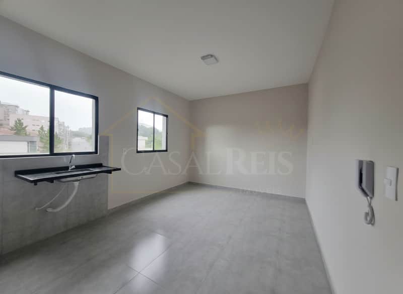 Sala clara com pia, piso cinza e janelas amplas. Ambiente arejado e iluminado.