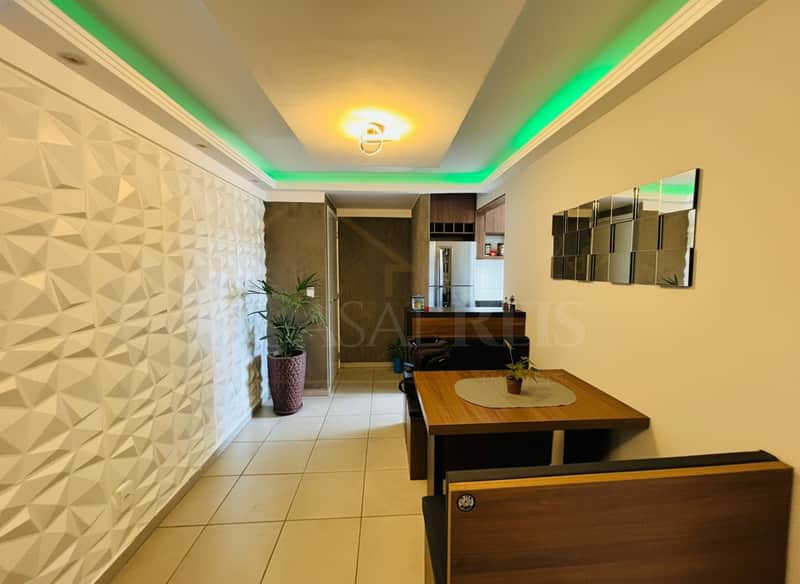 Sala decorada com parede 3D, mesa de jantar e iluminação verde no teto. Ambiente moderno e aconchegante.