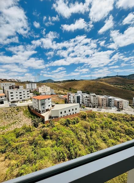 Vista externa de casas modernas em área verde sob céu azul com nuvens.