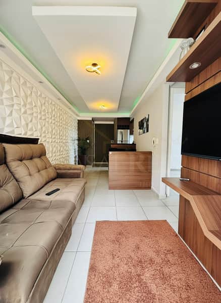 Sala moderna com sofá marrom, parede texturizada e teto iluminado. Decoração clean e aconchegante.