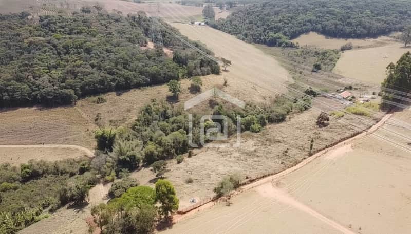 Vista aérea de área rural com pasto, mata nativa e rede elétrica.