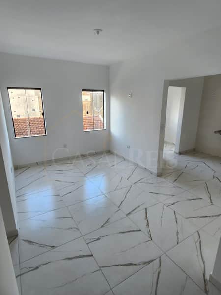 Sala ampla e clara com piso em porcelanato marmorizado e duas janelas.