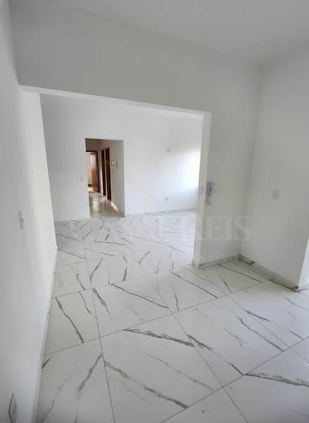 Sala ampla e iluminada com piso de porcelanato branco e detalhes em mármore cinza.