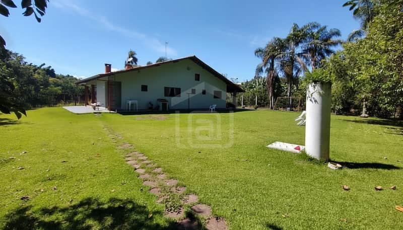 Casa com gramado, área externa espaçosa. Destaque para vegetação, árvores e construção.