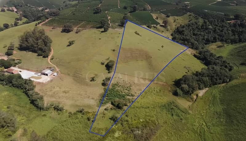 Terreno rural com pasto verde delimitado. Vista aérea da propriedade com vegetação e casa.