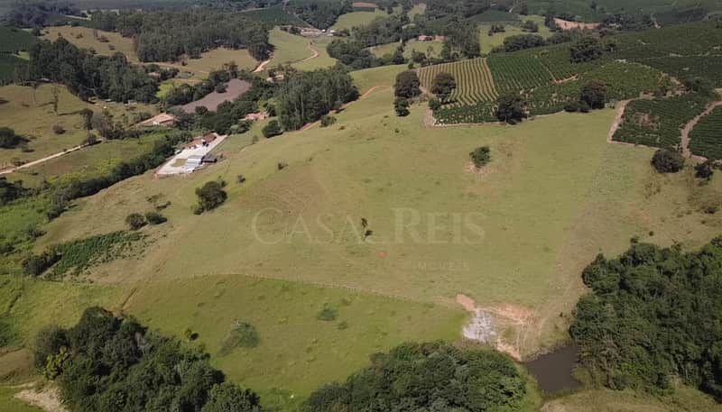 Vista aérea de fazenda com pasto verde, lago e plantações. Paisagem rural exuberante.