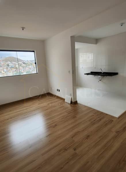 Sala com piso amadeirado e cozinha integrada com pia e azulejos brancos. Janela com vista da cidade.