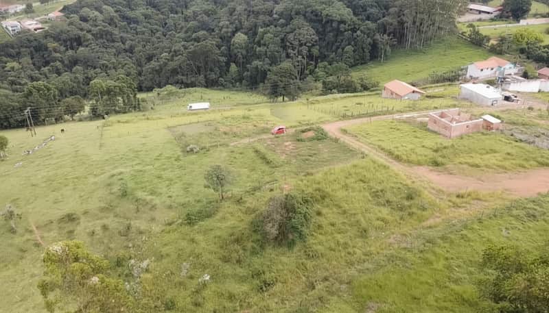 Vista aérea de área externa verde com casa em construção e vegetação.