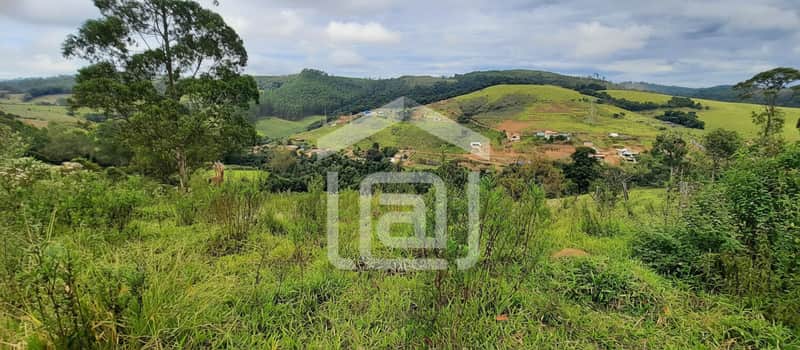Área externa com vegetação exuberante, vista para colinas e casas ao fundo. Paisagem natural.