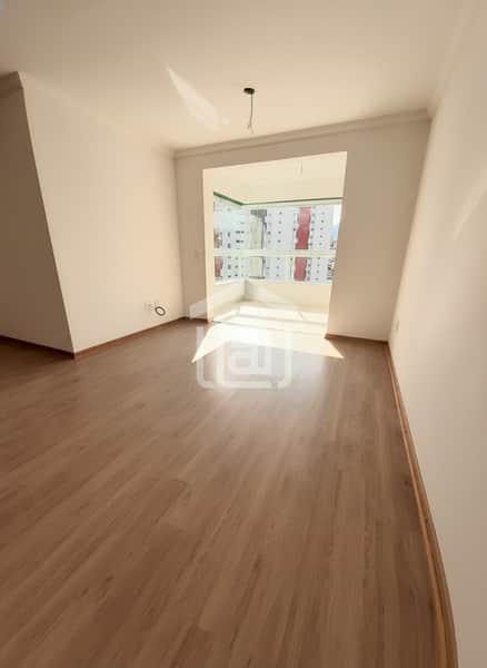 Sala ampla e iluminada com piso amadeirado e vista da cidade. Acabamento clean e moderno.