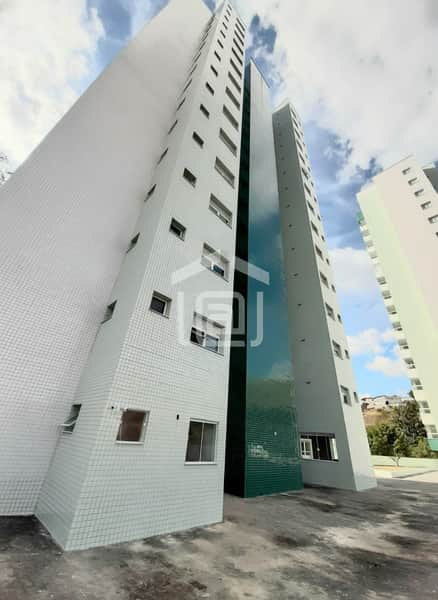 Fachada de prédio alto com revestimento em azulejo claro e detalhes em verde. Arquitetura moderna e céu azul.