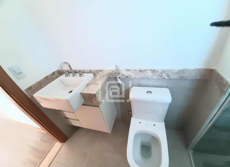 Banheiro claro com pia moderna, bancada em mármore e vaso sanitário branco. Ambiente clean e bem iluminado.