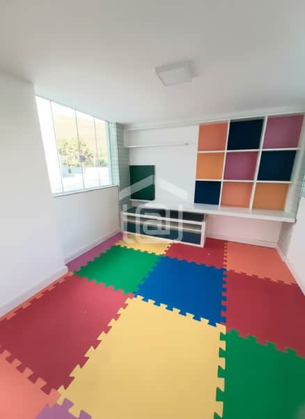 Quarto infantil colorido com tatame, estante nicho e janela ampla. Ambiente alegre e iluminado.