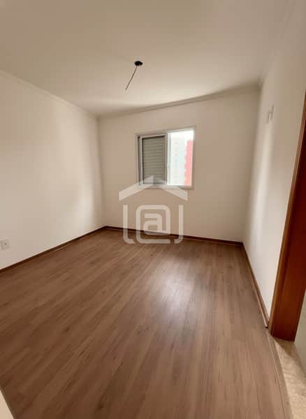 Quarto claro com piso amadeirado e janela com persiana. Ambiente arejado e iluminado.