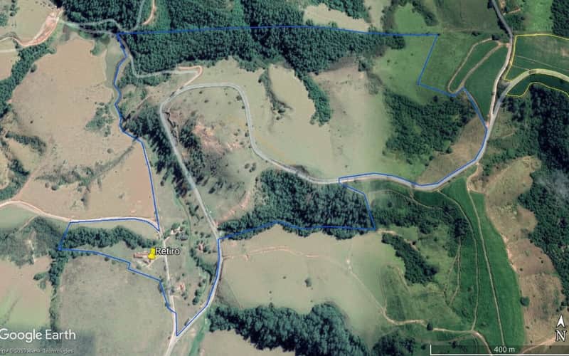 Fazenda com pasto, mata nativa e estrada sinuosa. Vista aérea da propriedade rural em área verde.