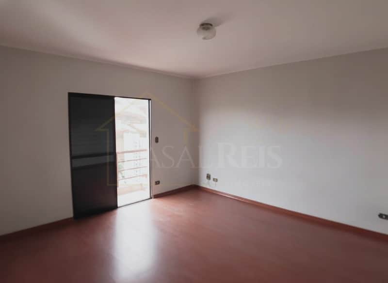 Quarto amplo com piso de madeira e porta para varanda. Ambiente claro e arejado.