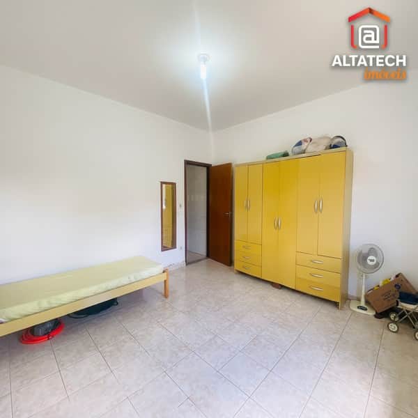 Quarto com cama, armário amarelo, piso cerâmico e boa iluminação. Ambiente amplo e arejado.