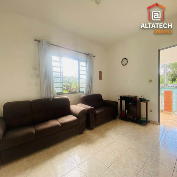 Sala aconchegante com sofás marrons, piso cerâmico e janela iluminada. Decoração simples e ambiente convidativo.