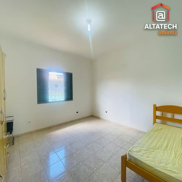 Quarto claro com cama de solteiro, piso cerâmico e janela com grades. Ambiente arejado e iluminado.