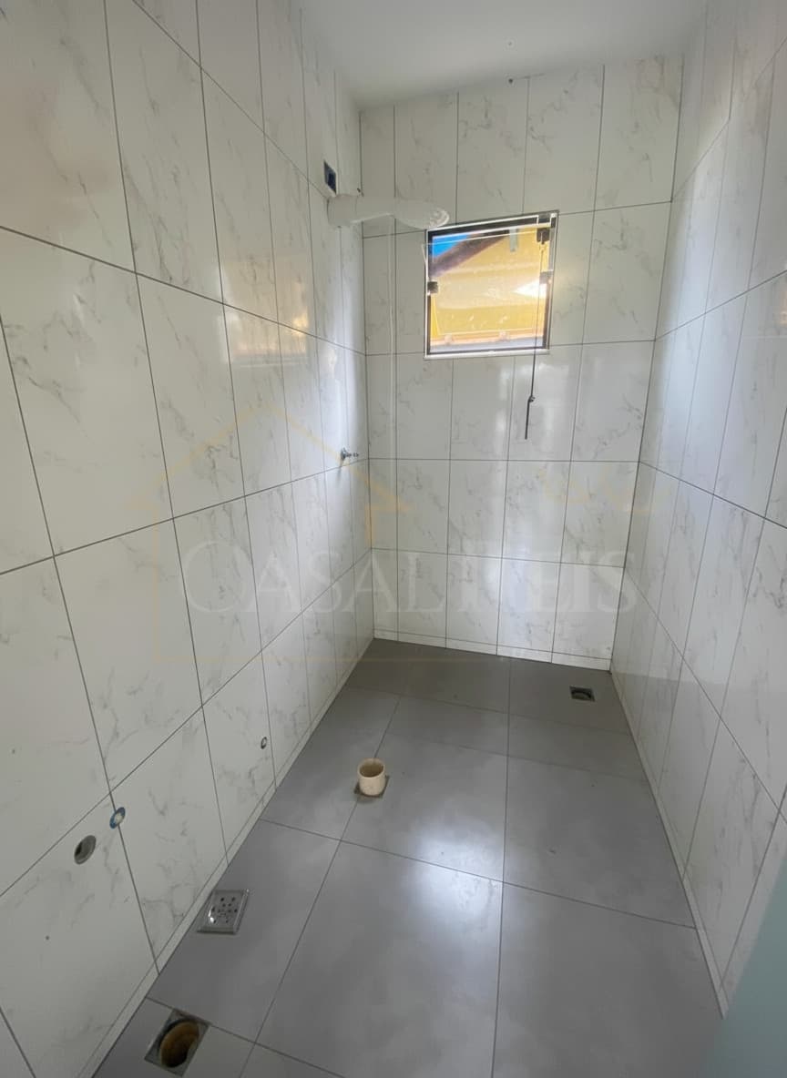 Banheiro com revestimento marmorizado claro, piso cinza e janela. Ambiente clean e iluminado.
