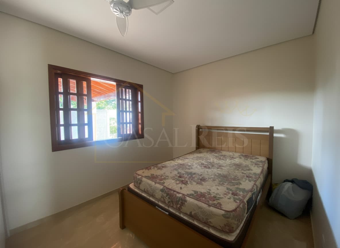 Quarto com cama de madeira, janela aberta e piso claro. Ambiente iluminado e arejado.