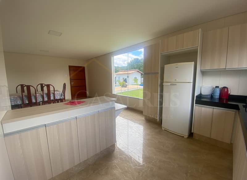 Cozinha ampla com ilha, armários planejados e piso em porcelanato. Janela com vista para área externa.
