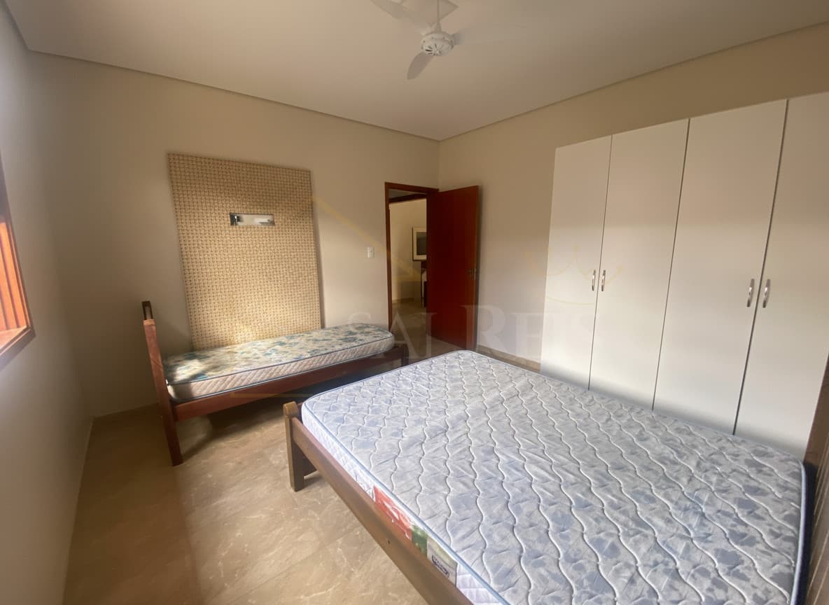 Quarto com duas camas de solteiro, armário branco e piso de mármore. Ambiente claro e arejado.