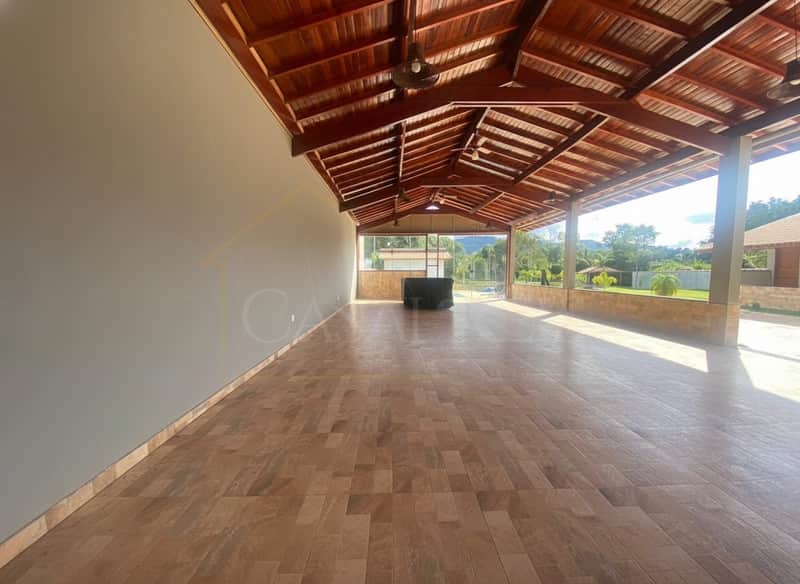 Ampla área externa com piso cerâmico, teto de madeira e vista para a natureza. Ideal para eventos e lazer.